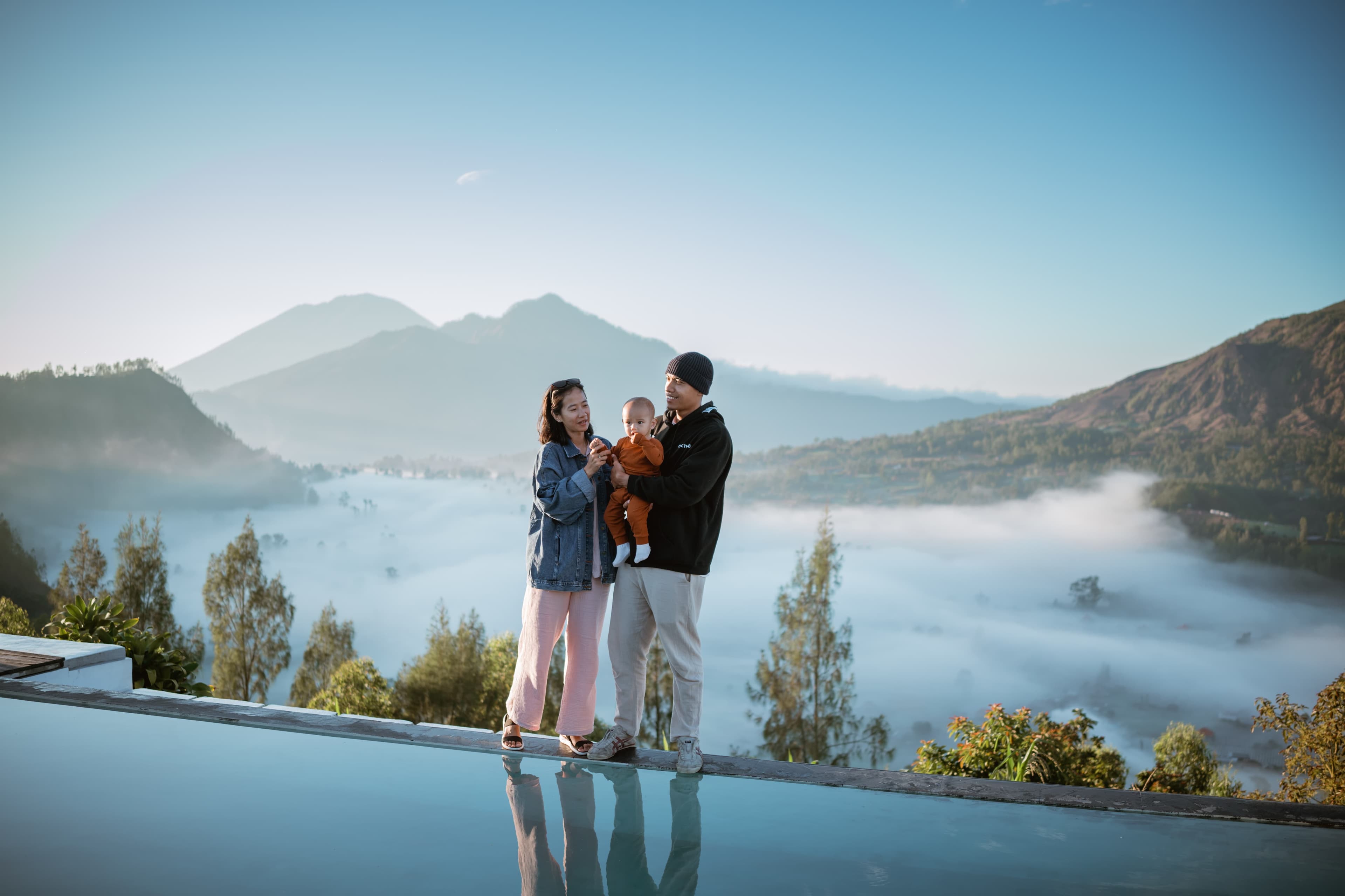 Family at an infinity pool overlooking misty mountains